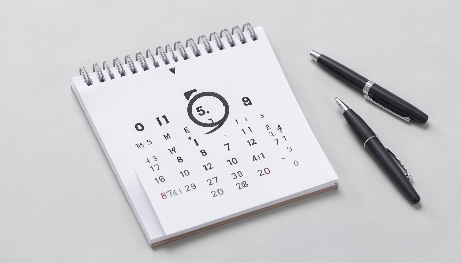 A calendar with a circled date and a pen beside it, clean desk setup, soft grey and white palette